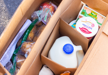 Box of milk, bread, fruits, and vegetables