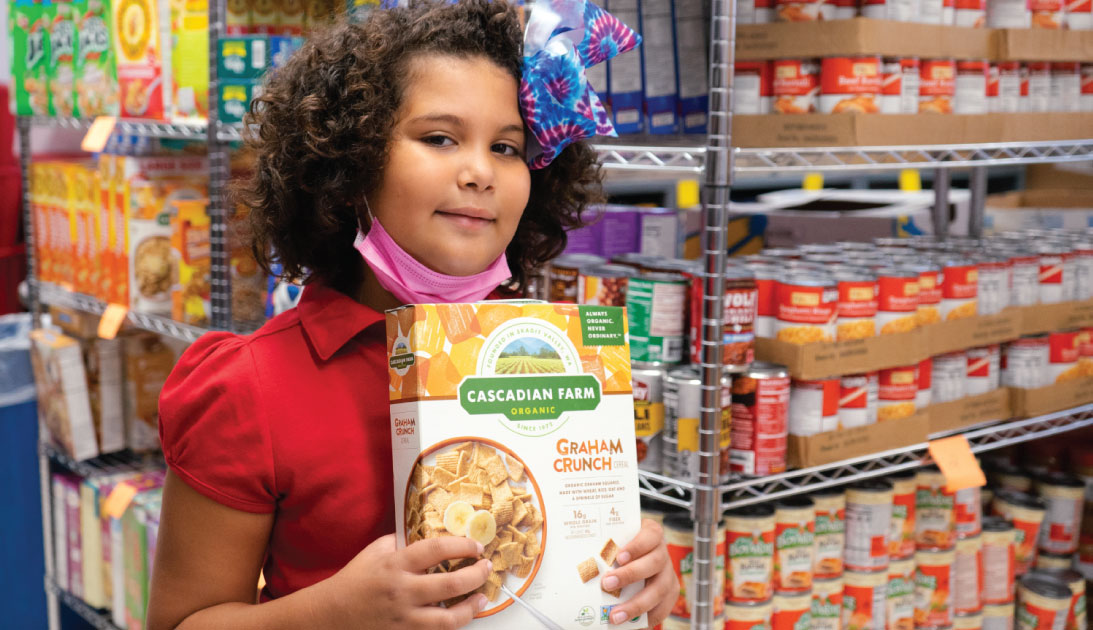 Little girl smiles for a picture holding a box of cereal