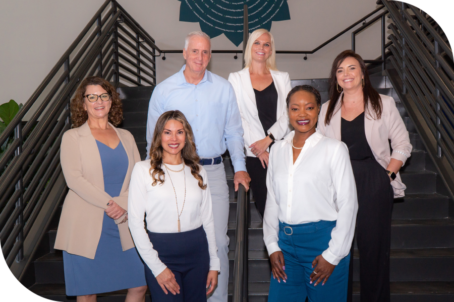 Feeding Tampa Bay's leaders standing together on the lobby staircase in professional attire, smiling brightly.