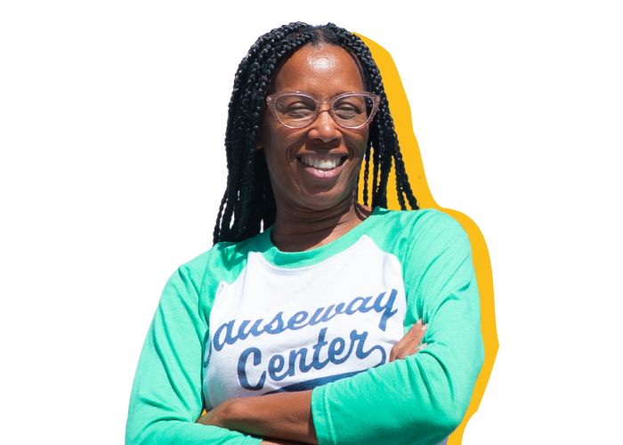 A woman graduate from Feeding Tampa Bay's FreshForce CDL truck driving track smiling with her arms crossed proudly.